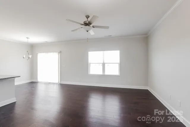 an empty room with wooden floor closet and windows