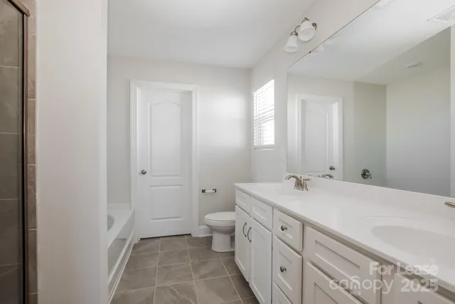 a spacious bathroom with a granite countertop sink a toilet and a mirror