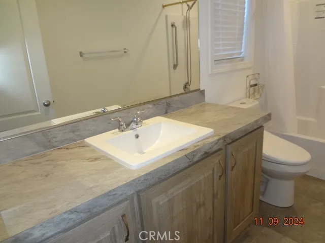 a bathroom with a granite countertop sink and a toilet