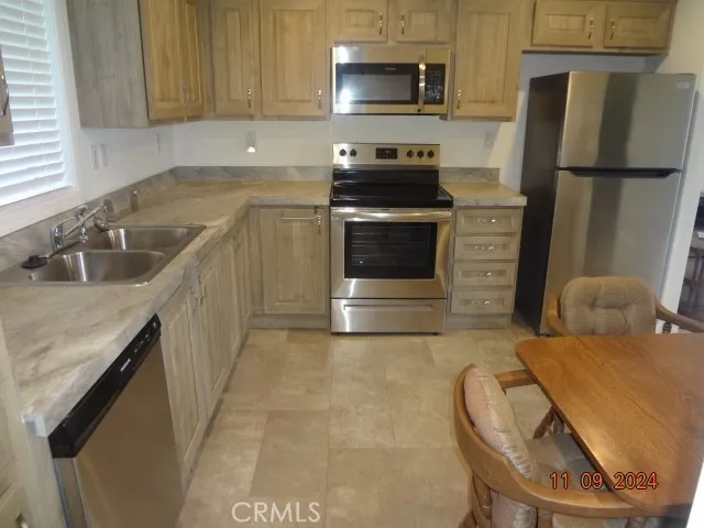 a kitchen with stainless steel appliances a stove a sink and a refrigerator