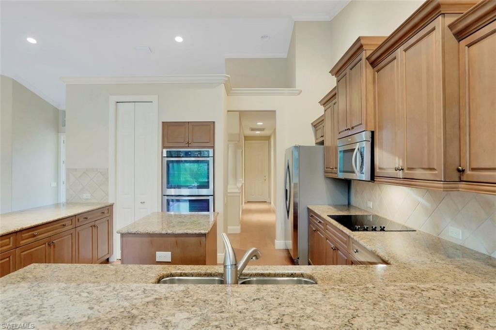 7856 Classics Drive Naples, FL 34113 - Photo 12 of 25 a view of a kitchen with stainless steel appliances kitchen island granite countertop a refrigerator and a sink