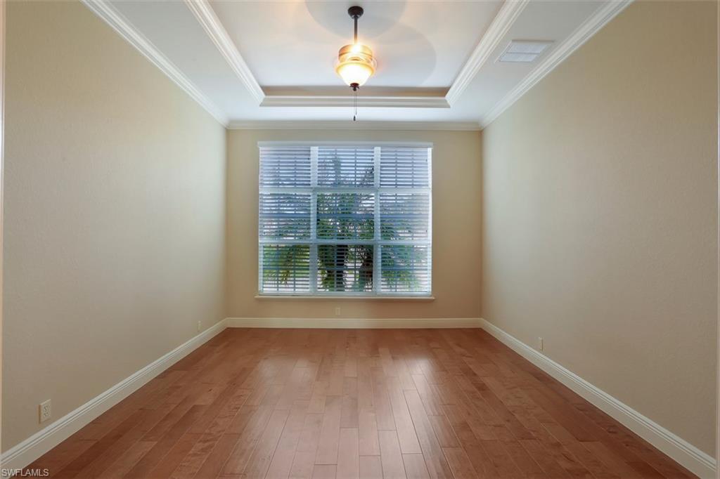 7856 Classics Drive Naples, FL 34113 - Photo 15 of 25 an empty room with wooden floor chandelier and windows