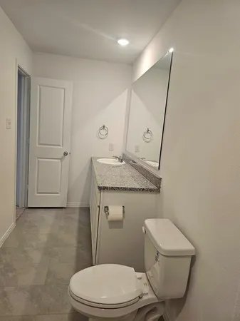 a bathroom with a granite countertop toilet sink and mirror