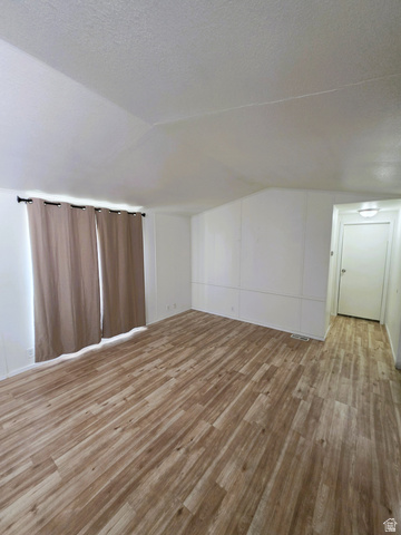 1604 180 East Tooele, UT 84074 - Photo 4 of 16 Expansive interior space featuring wood-finish flooring, light-toned walls, and a window with curtain rod