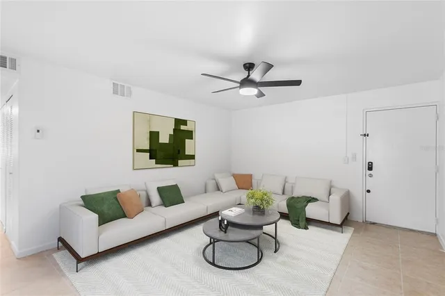 a living room with furniture a white walls and a ceiling fan