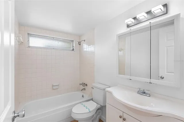 a bathroom with a bathtub shower sink vanity mirror and toilet