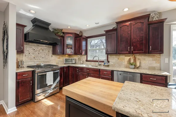 a kitchen with stainless steel appliances granite countertop wooden floors stove and white cabinets