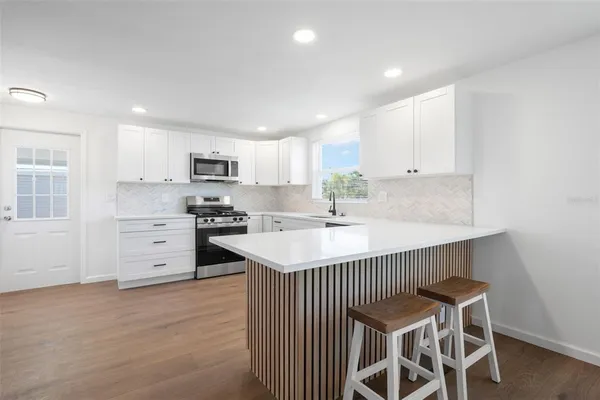 a kitchen with cabinets stainless steel appliances a sink and a window