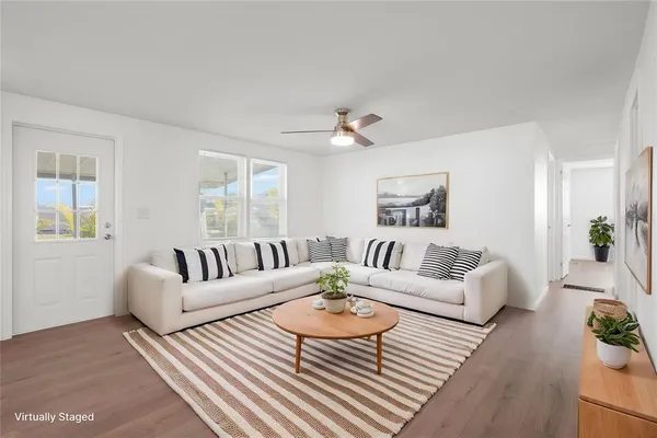 an empty room with wooden floor chandelier fan and windows