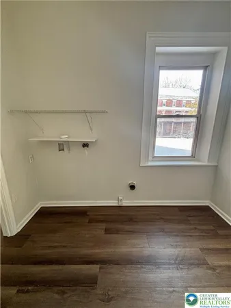 an empty room with wooden floor and window