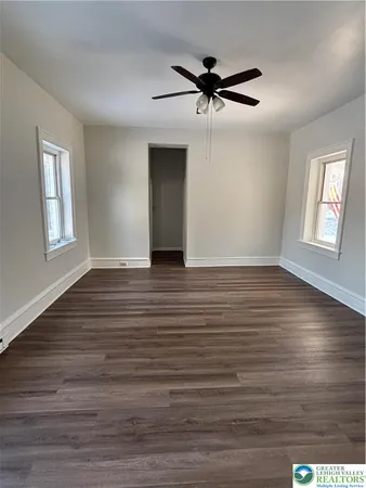 a view of empty room with wooden floor and window