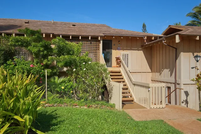 a view of a house with brick walls and a small yard with plants