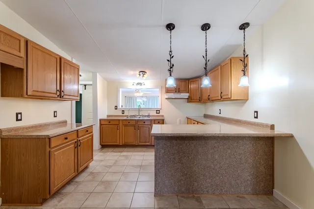 a kitchen with kitchen island granite countertop a sink a counter top space stainless steel appliances and cabinets