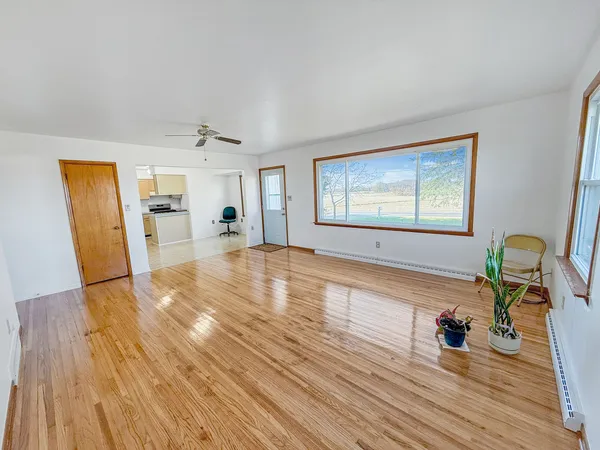 a view of empty room with wooden floor and fan