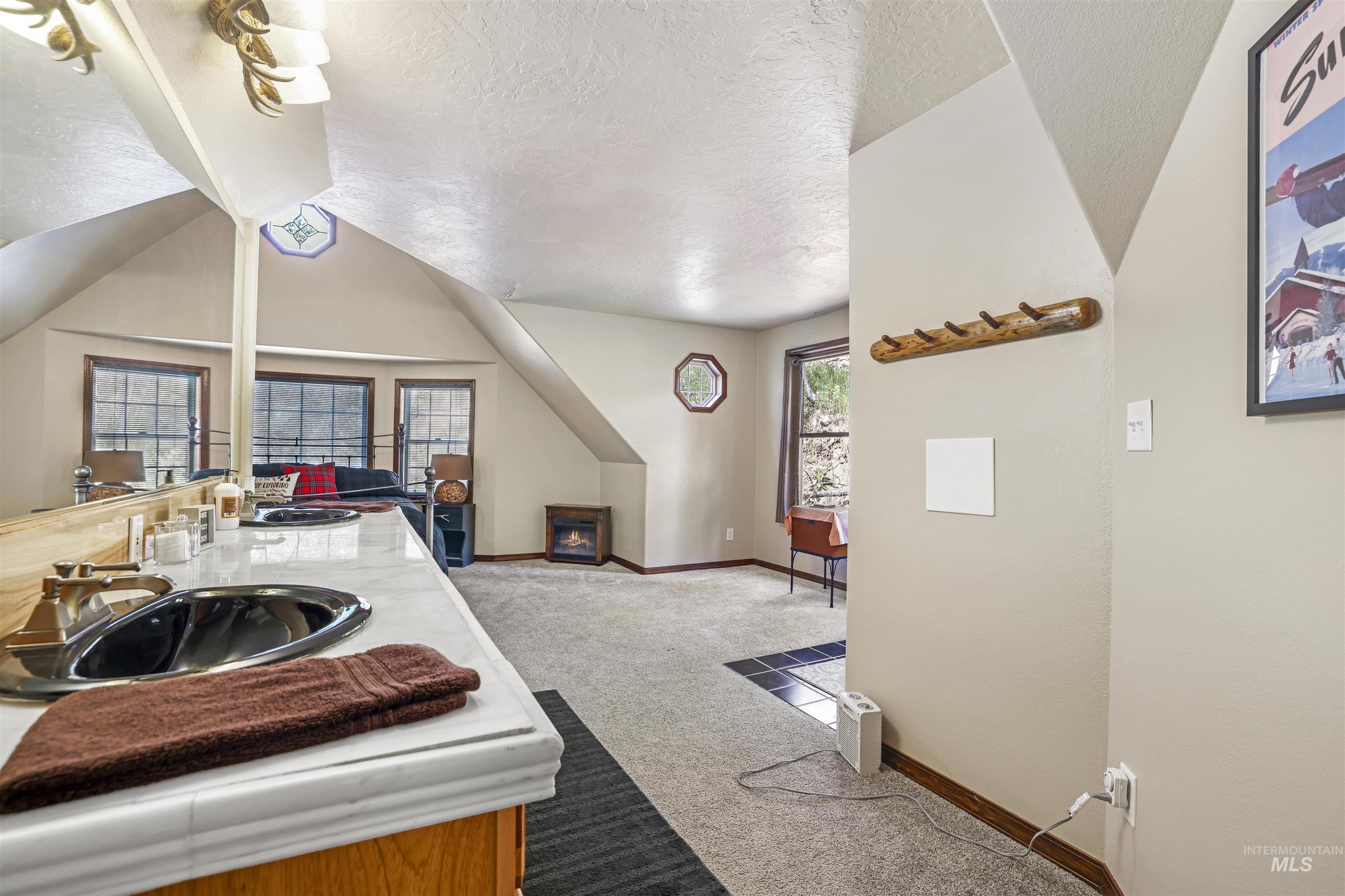 224 Dakota Road Mountain Home, ID 83647 - Photo 30 of 50 Spacious loft area featuring a built-in wet bar with a countertop and undermount sink, multiple large windows, wall-to-wall carpeting, and a corner fireplace