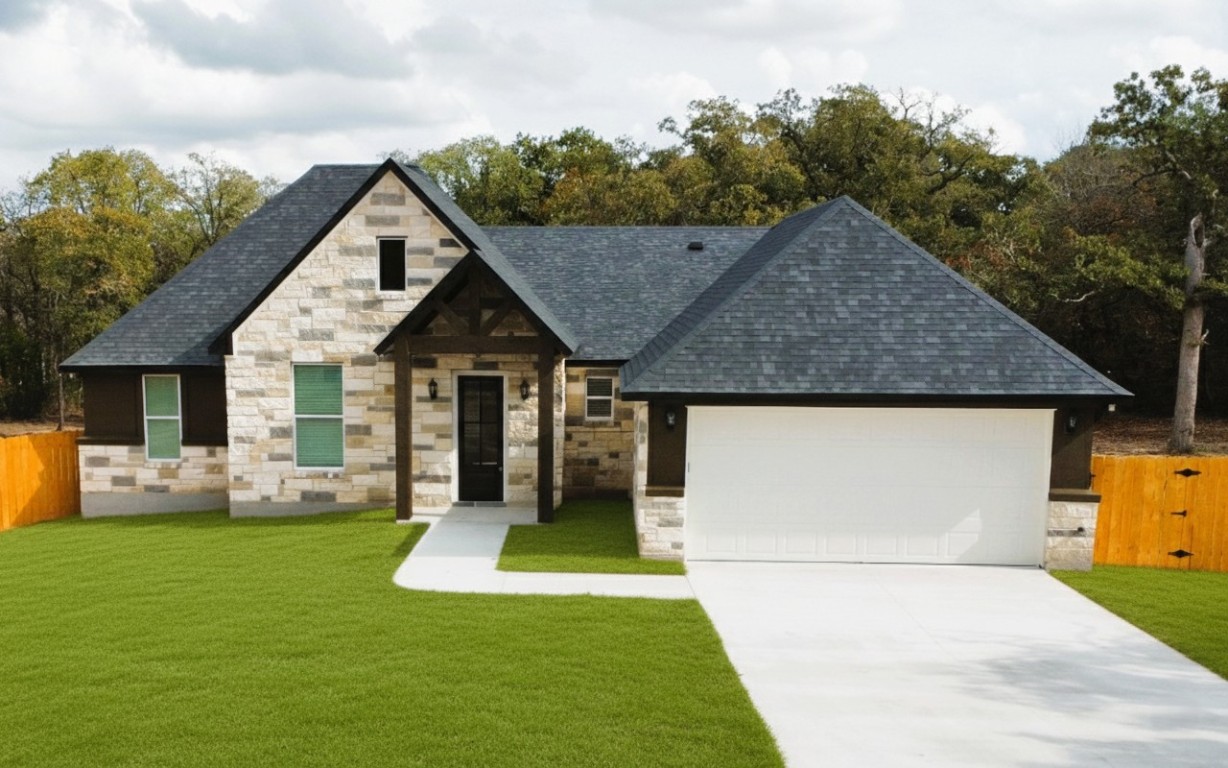 View of front facade featuring stone siding, concrete driveway, an attached garage, and a gate