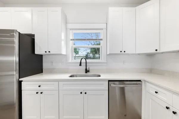 a kitchen with stainless steel appliances white cabinets and a window