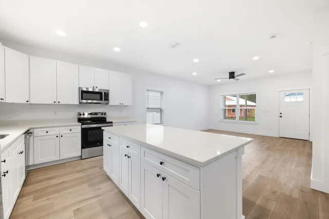 a kitchen with granite countertop white cabinets and white appliances