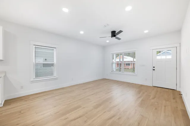 an empty room with wooden floor and windows