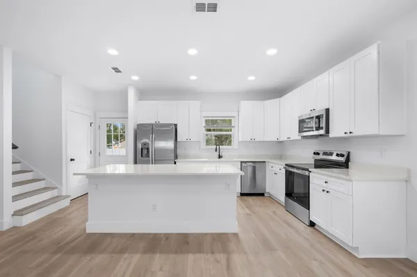 a large white kitchen with stainless steel appliances granite countertop a stove and a sink
