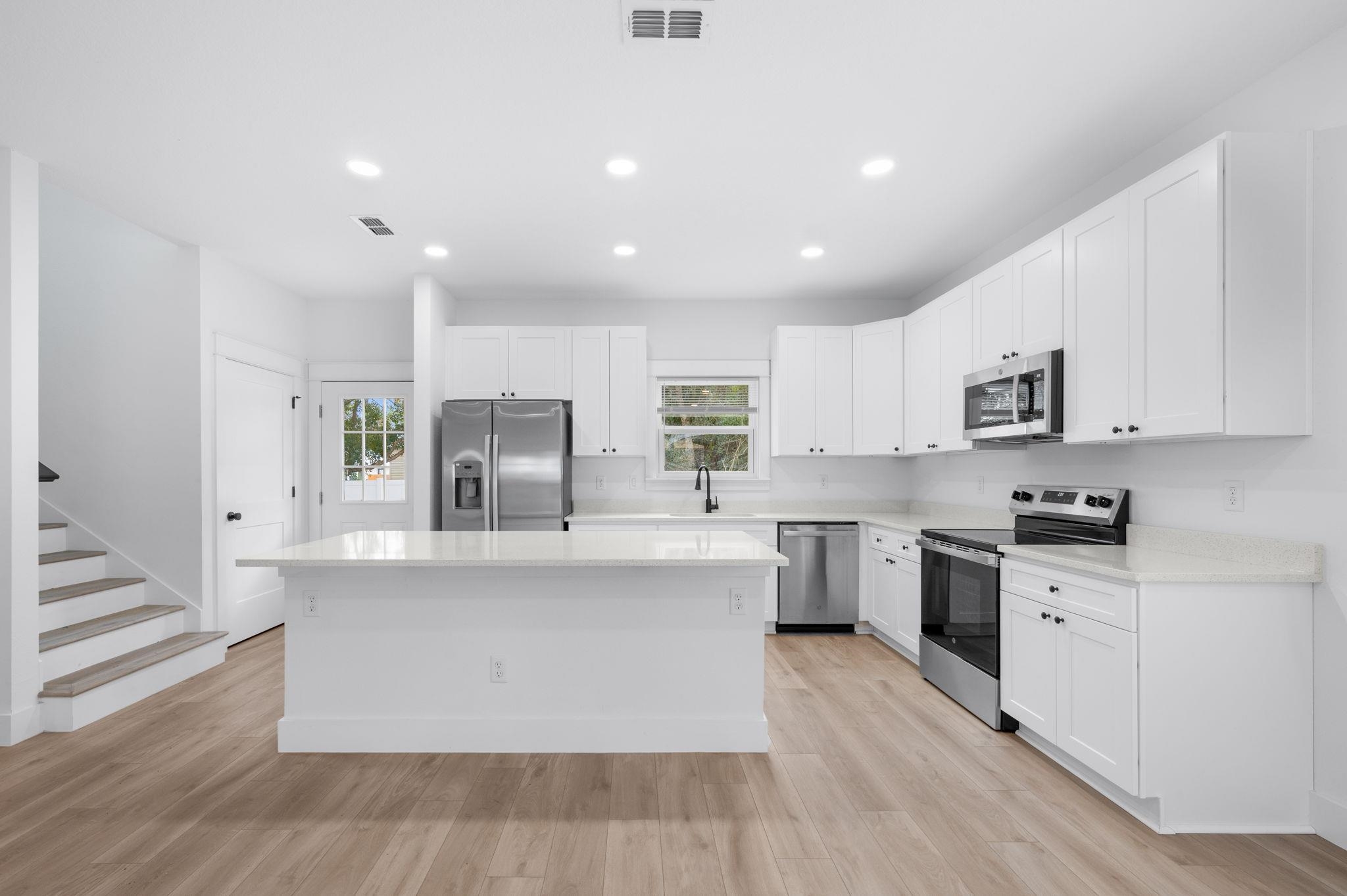 863 West 12th Street St. Augustine, FL 32084 - Photo 10 of 41 a large white kitchen with stainless steel appliances granite countertop a stove and a sink