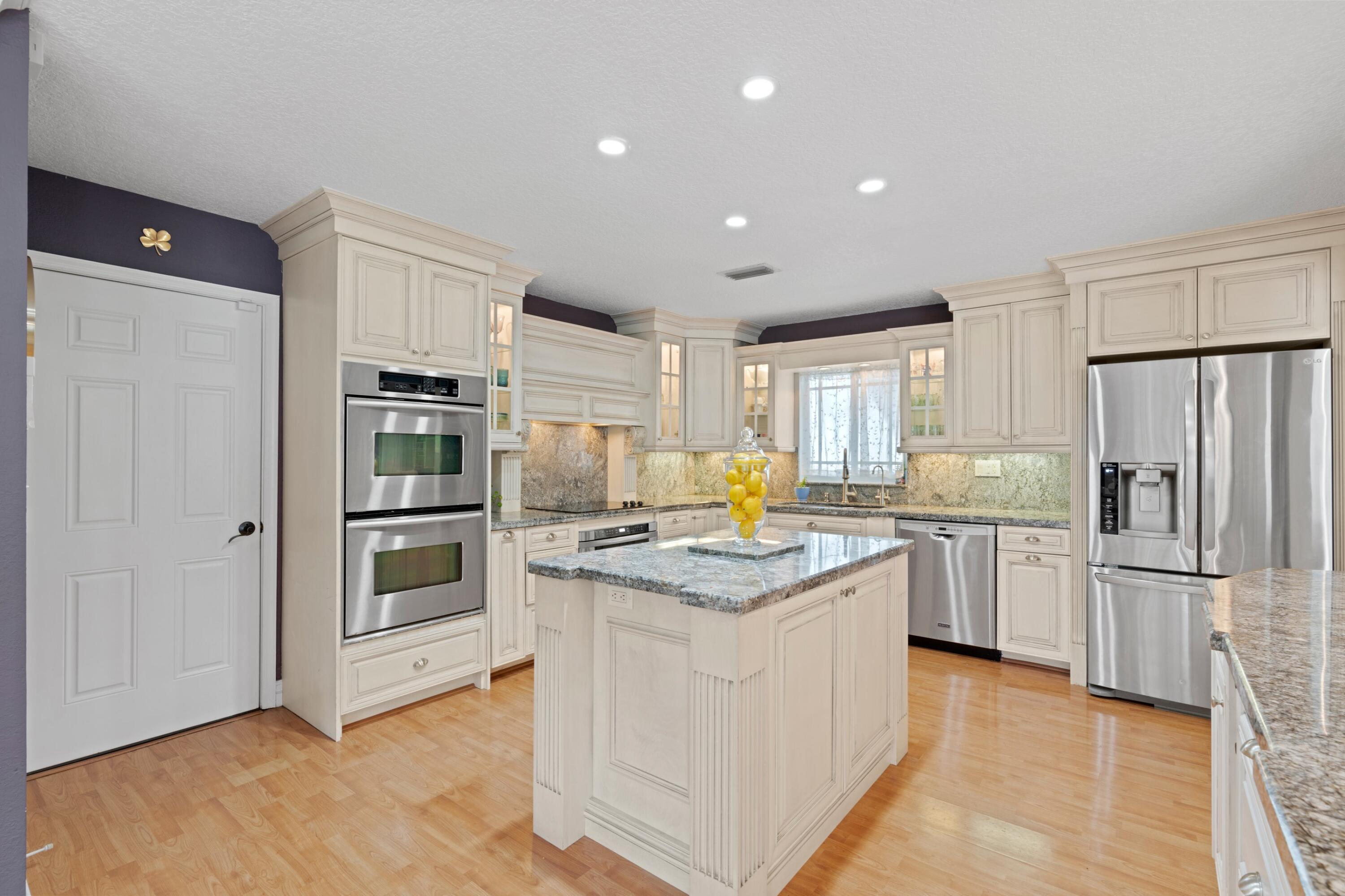 10238 Crosswind Road Boca Raton, FL 33498 - Photo 12 of 42 a kitchen with white cabinets and stainless steel appliances