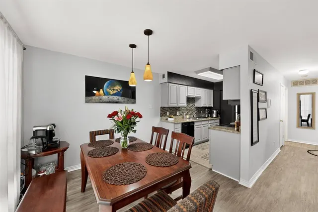 a kitchen with stainless steel appliances granite countertop a stove a refrigerator a kitchen island a dining table and chairs with wooden floor