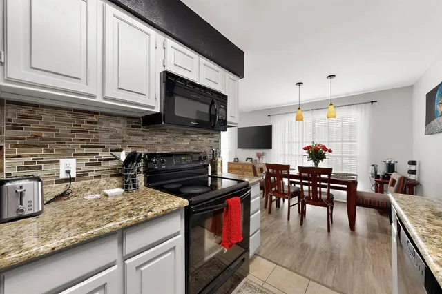 a kitchen with stainless steel appliances granite countertop a stove top oven a sink a dining table and chairs with wooden floor