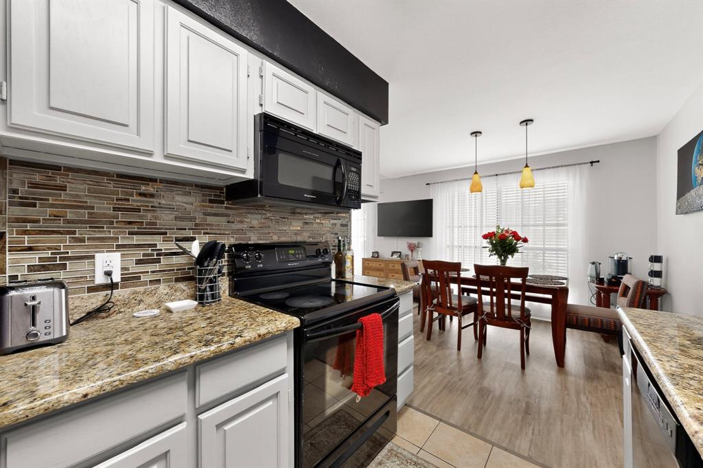 324 West Harwood Road, Unit A Hurst, TX 76054 - Photo 15 of 27 a kitchen with stainless steel appliances granite countertop a stove top oven a sink a dining table and chairs with wooden floor