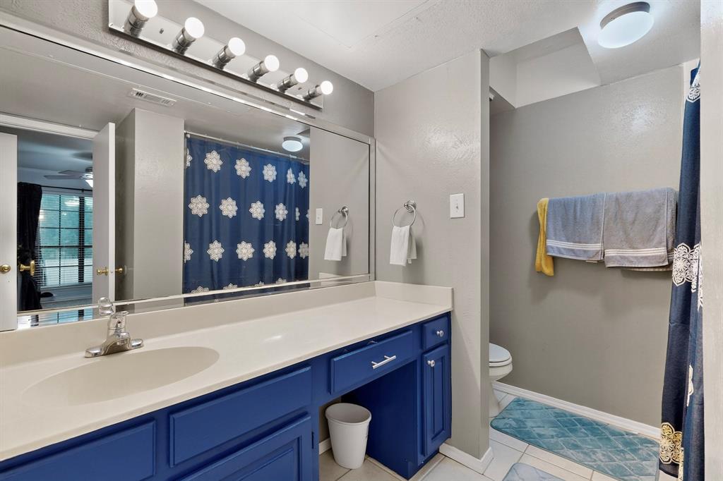 324 West Harwood Road, Unit A Hurst, TX 76054 - Photo 22 of 27 a bathroom with a granite countertop sink a toilet and a mirror