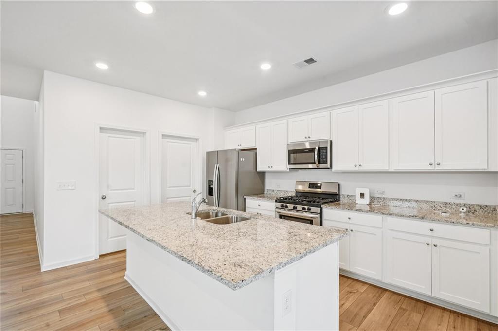 3853 Rustic Barn Way Loganville, GA 30052 - Photo 3 of 22 a kitchen with stainless steel appliances granite countertop a sink stove and refrigerator