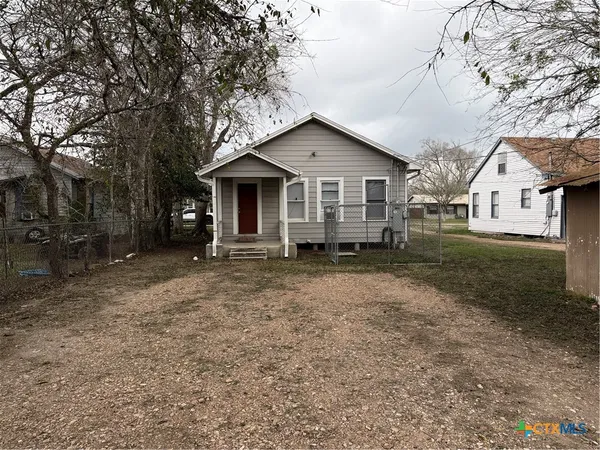 a view of a house with a yard and large trees
