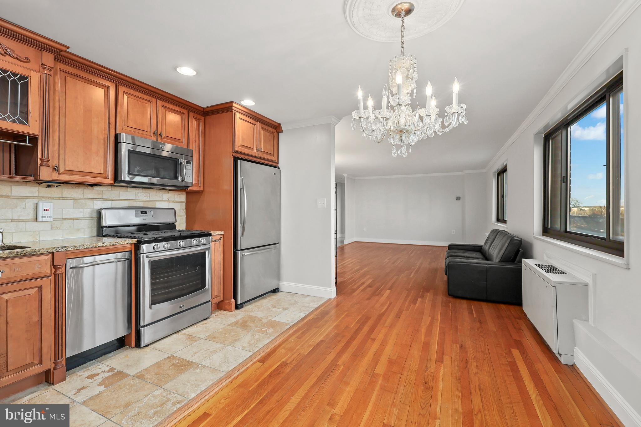 1200 South Arlington Ridge Road, Unit 404 Arlington, VA 22202 - Photo 8 of 32 a kitchen with stainless steel appliances granite countertop a stove top oven a sink dishwasher a dining table and chairs with wooden floor