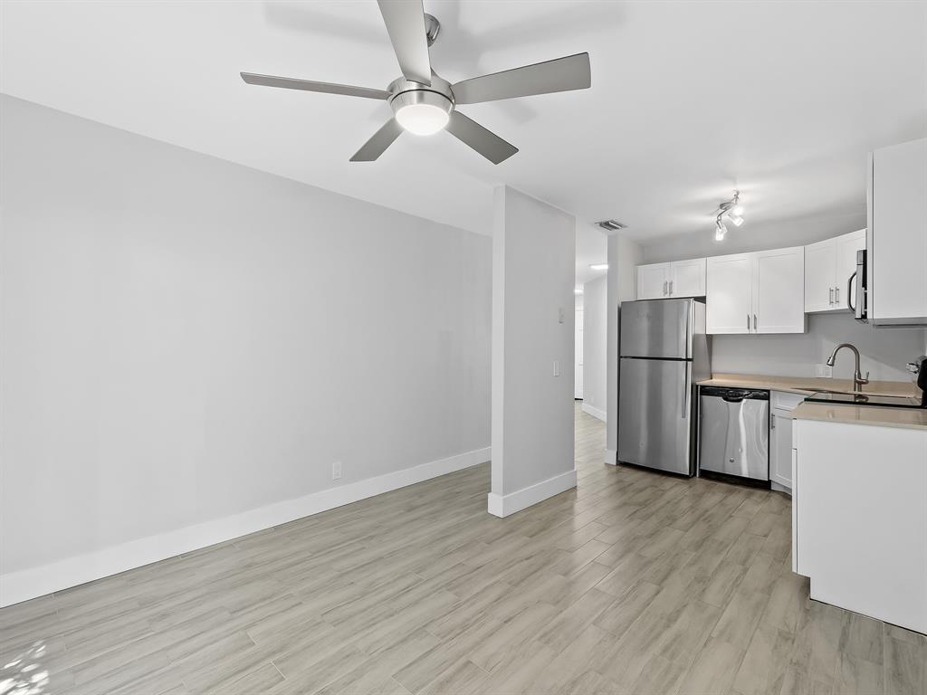 3208 Northeast 7th Street, Unit C Pompano Beach, FL 33062 - Photo 4 of 10 a kitchen with stainless steel appliances wooden floor sink and cabinets