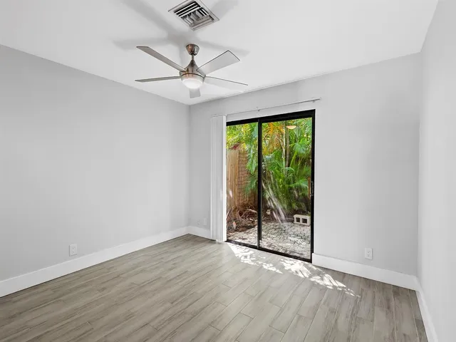 an empty room with wooden floor fan and windows