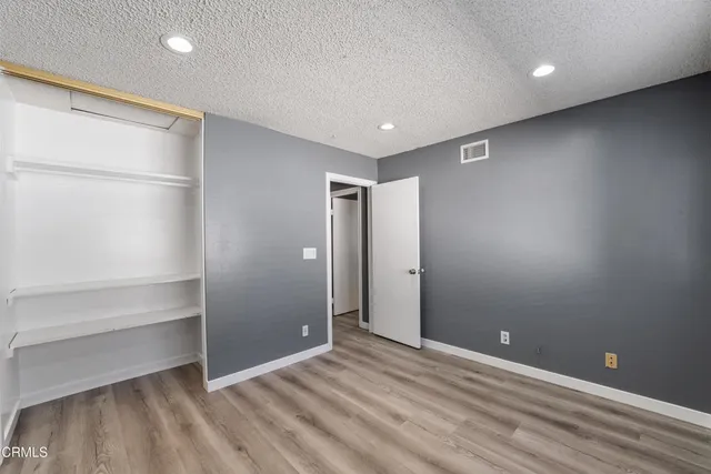 a view of an empty room with wooden floor and a ceiling fan
