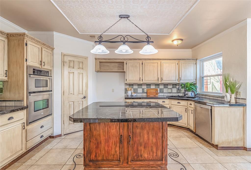 716 Bridget Way Hurst, TX 76054 - Photo 14 of 33 Kitchen with backsplash, decorative light fixtures, stainless steel appliances, a center island, and light wood finish cabinetry