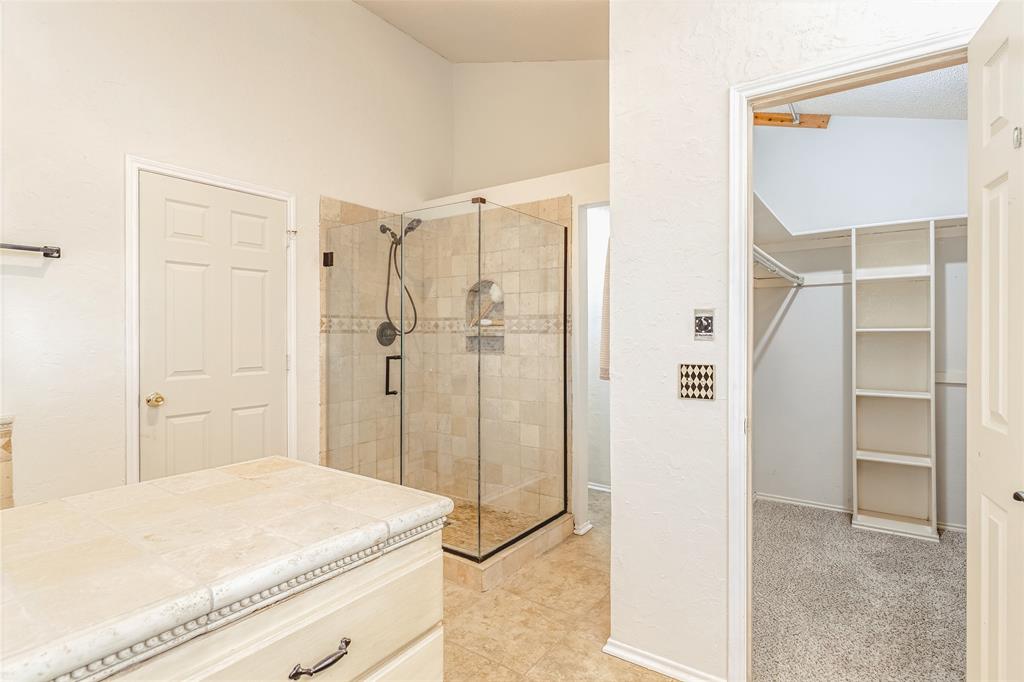 716 Bridget Way Hurst, TX 76054 - Photo 20 of 33 Bathroom featuring a spacious closet, a shower stall, light colored carpet, light tile patterned floors, and vaulted ceiling