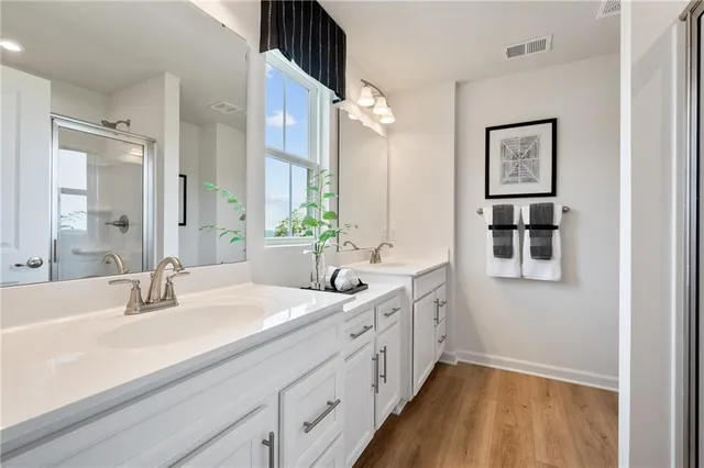 a bathroom with double vanity sinks a mirror and a shower