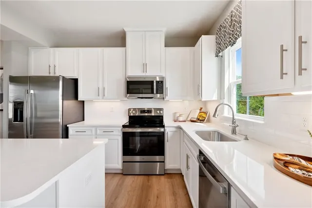 a kitchen with stainless steel appliances a sink a stove a microwave a sink a refrigerator and cabinets