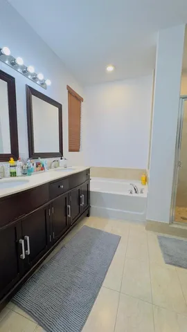 a spacious bathroom with a tub double vanity sink and a mirror