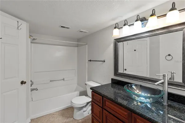 a bathroom with a granite countertop sink a toilet and shower