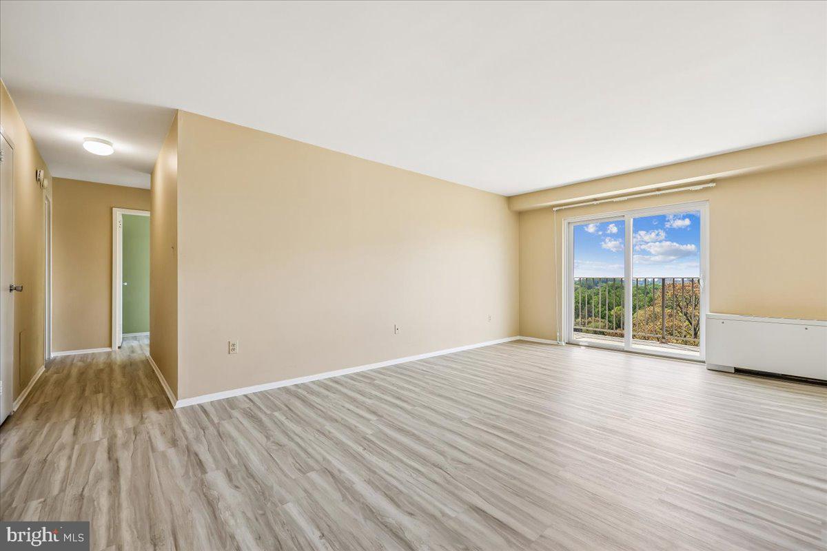 1111 University Boulevard West, Unit 1106A Silver Spring, MD 20902 - Photo 4 of 35 a view of an empty room with wooden floor and a window