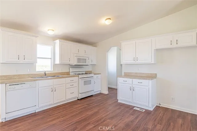 a kitchen with granite countertop white cabinets and white appliances