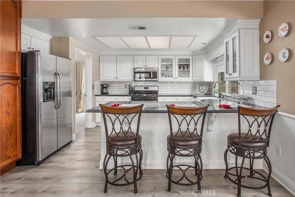 1125 Vía Nice Redlands, CA 92374 - Photo 15 of 50 a kitchen with stainless steel appliances granite countertop a table and chairs