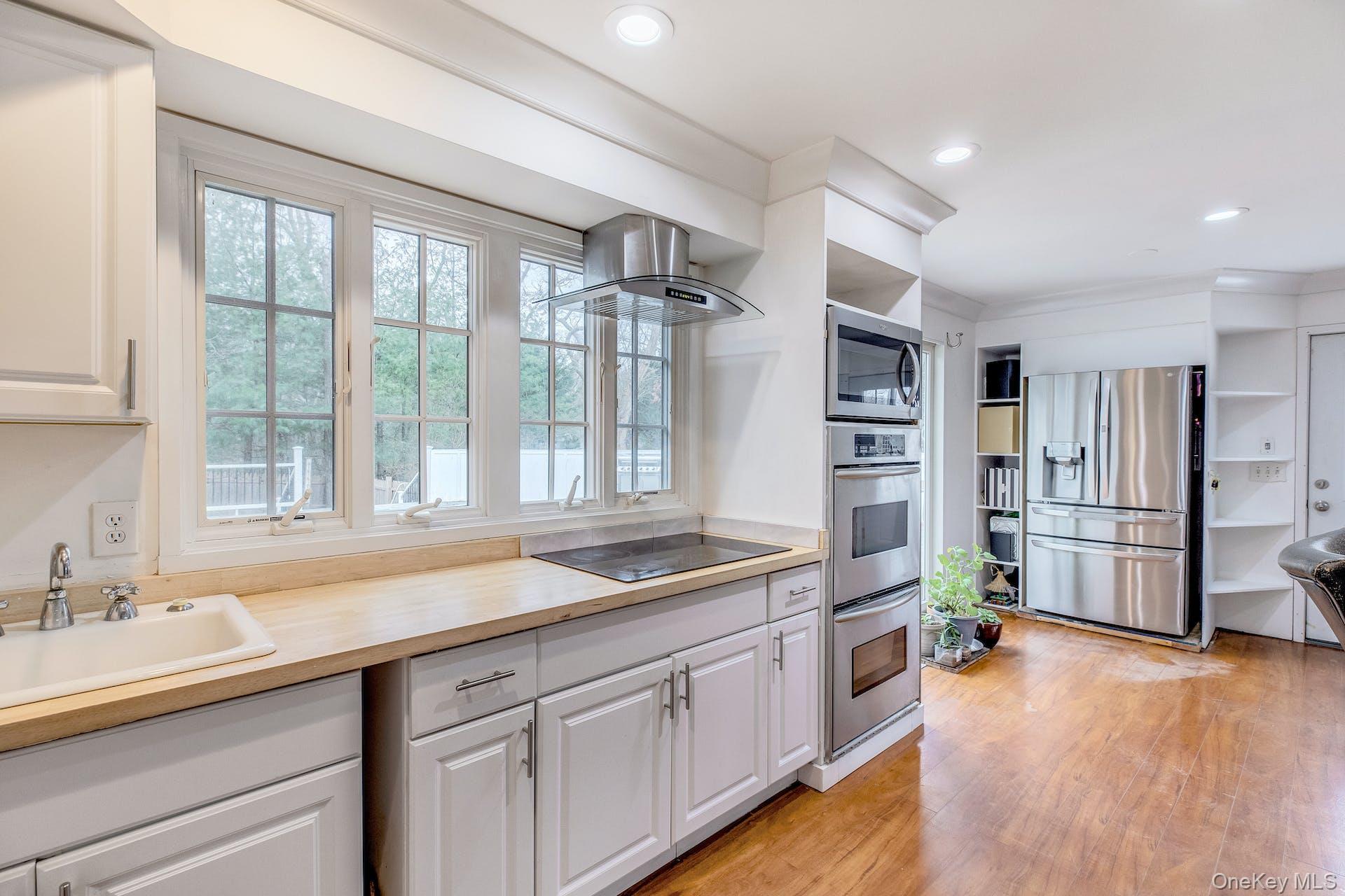 7 George Street Hampton Bays, NY 11946 - Photo 7 of 11 Kitchen featuring white cabinetry, wood-finish flooring, and recessed lighting