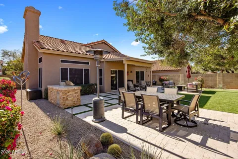 a view of a patio with table and chairs potted plants and a large tree