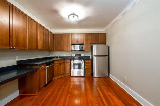 a kitchen with granite countertop wooden floors stainless steel appliances and cabinets