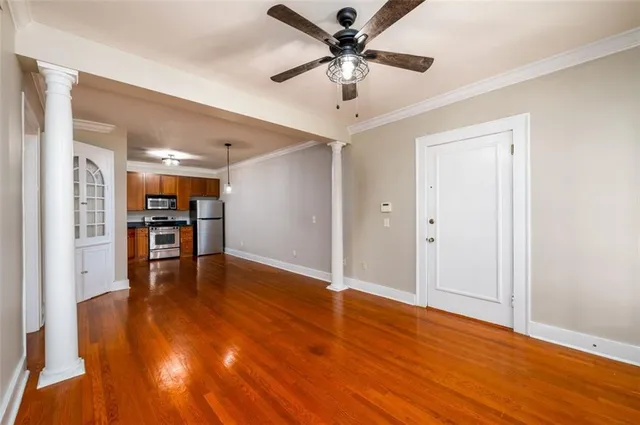a view of an empty room with wooden floor and a ceiling fan