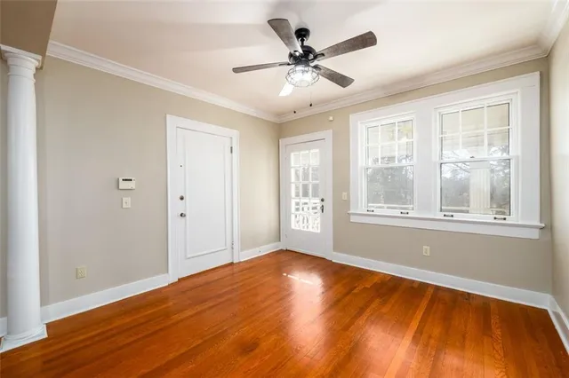 a view of an empty room with wooden floor and a window